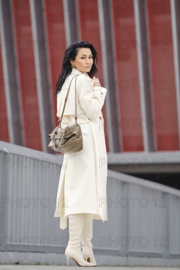 A woman confidently strolls down a modern urban street during autumn, she stopped and look back