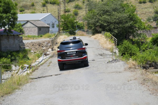 An SUV crosses a damaged bridge in a green, rural area, Toyota Fortuner on bridge over the Debed River, Ayrum, Tavush province, Tavush, Armenia