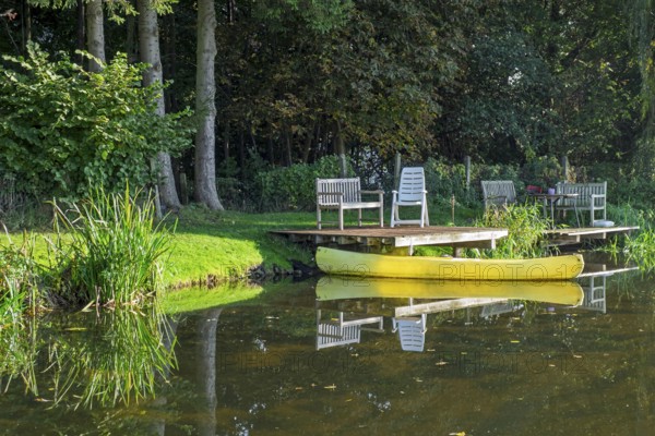 A jetty with benches and a yellow canoe on a quiet river, Dinkel River, Heek-Nienborg, Münsterland, North Rhine-Westphalia, Germany