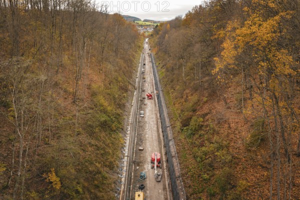 An autumn construction site in a wooded area, seen from a bird's eye view, with diverse autumn trees, construction of the Hermann Hesse Railway, Im Hau, Calw, Germany