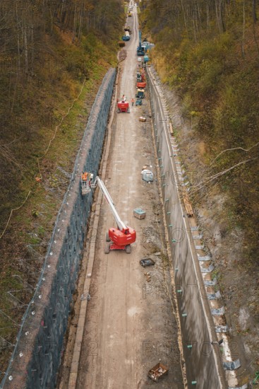 Construction work on a path in a wooded area with machines and a lift, construction of the Hermann Hesse Railway, Im Hau, Calw, Germany