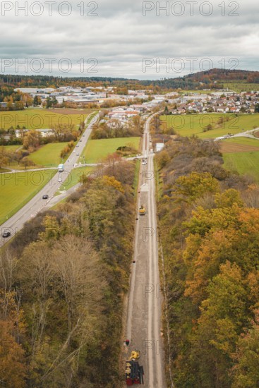 Construction site along a road in an autumn landscape near a village seen from the air, construction of the Hermann Hesse Railway, Im Hau, Calw, Germany