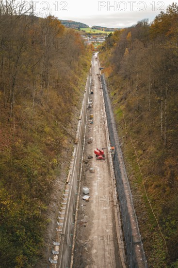 View of a construction site in a wooded autumn landscape with construction equipment and excavation work, construction of the Hermann Hesse Railway, Im Hau, Calw, Germany