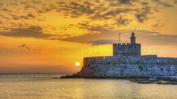 Agios Nikolaos fortress, glowing sunrise behind a castle by the sea, conveys peace, UNESCO World Heritage Site, Old Town of Rhodes Town, Rhodes, Dodecanese, Greece