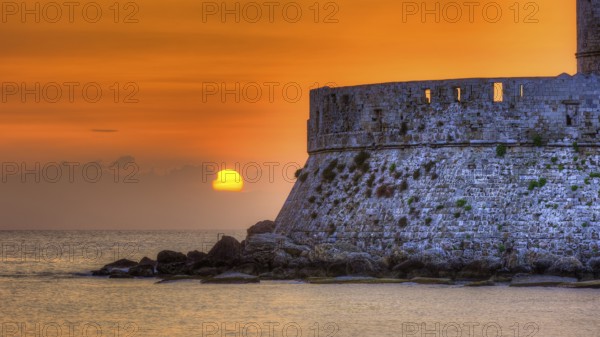 Agios Nikolaos fortress, sunrise behind an old castle wall with gentle sea waves, UNESCO World Heritage Site, Old Town of Rhodes Town, Rhodes, Dodecanese, Greece