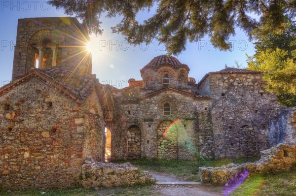Abandoned stone church in sunlight, surrounded by trees and medieval atmosphere, UNESCO World Heritage Site, Agia Sophia Church, Mistra, Mystra, Byzantine City, Peloponnese, Greece