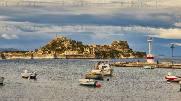 View of an island with fortress and small boats in the water under cloudy sky, UNESCO World Heritage Site, Old Town of Corfu, Corfu, Corfu, Ionian Islands, Greece