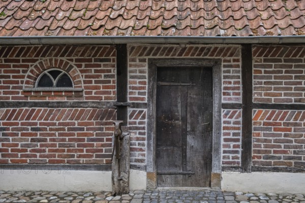 Wooden door in a traditional brick frame wall with roof tiles, Münsterland, North Rhine-Westphalia, Germany