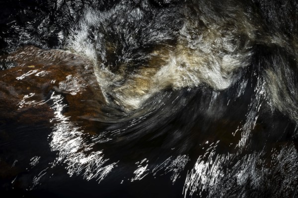 Stream flow with dark water, reflections and turbulences, long exposure, Sweden