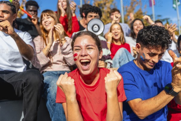 Young diverse fans sitting in a stadium enjoying a sporting event, celebrating and cheering for their team with excitement and passion, showing support and enthusiasm in a vibrant crowd