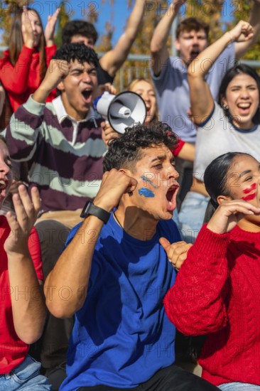 Young diverse people in a stadium are intensely cheering and shouting, supporting their team while showing excitement with face paint and a megaphone during a live event