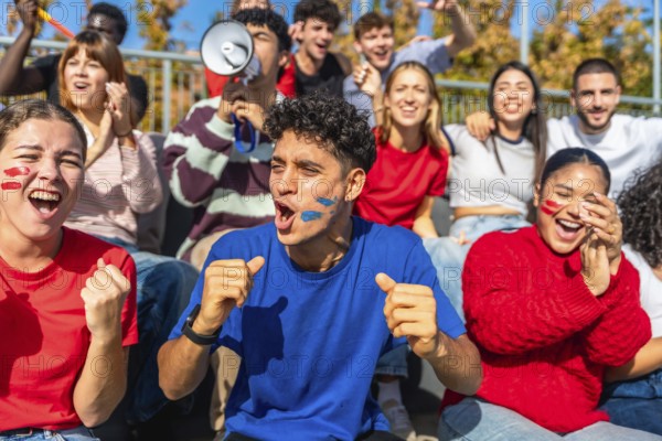 Multiracial young people celebrating and cheering passionately in a stadium, showing excitement and team spirit with painted faces while watching a live sport event