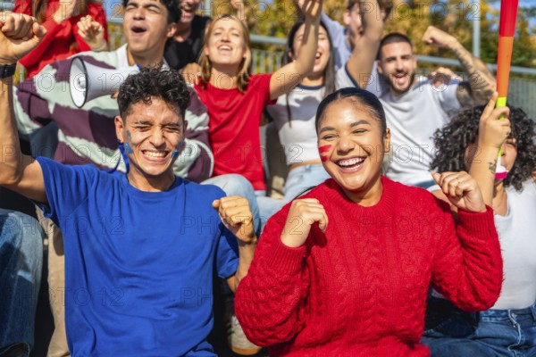 Diverse group of young sports fans cheering with painted faces and team colors in a stadium, celebrating together with joy, energy and unity during a daytime event