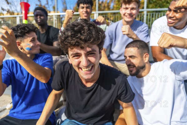 Young diverse male friends cheering in a sunlit stadium, celebrating their team with smiles, laughter and high energy while bonding over sport and shared excitement