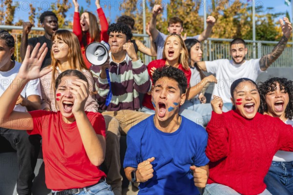 Enthusiastic young fans of diverse ethnicities and genders celebrating and cheering loudly, expressing excitement and support for their favorite team or sport in a stadium