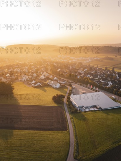 Aerial view of a village with fields at sunset and a modern building, Gechingen, Germany