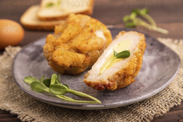 Chicken Schnitzel on gray plate with microgreen on brown wooden background and linen textile. side view, close up, selective focus