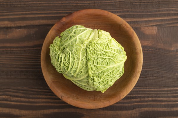 Green lettuce on plate on brown wooden background. Top view, copy space, flat lay. healthy food, vegetable, minimalism