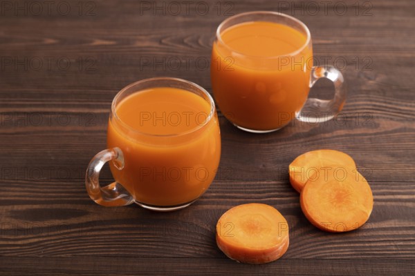 Two glasses with carrot juice, on wooden background. Diet, healthy eating concept. side view, close up, minimalism