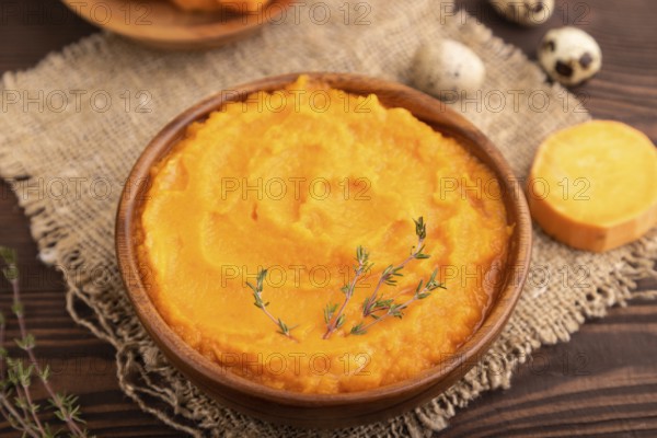 Sweet potato porridge in wooden bowl on wooden background and linen textile. Diet, healthy eating concept. side view, close up, minimalism, selective focus