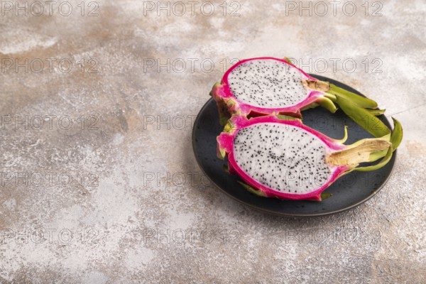Ripe Pitaya on blue plate on brown concrete background, side view, copy space, minimalism