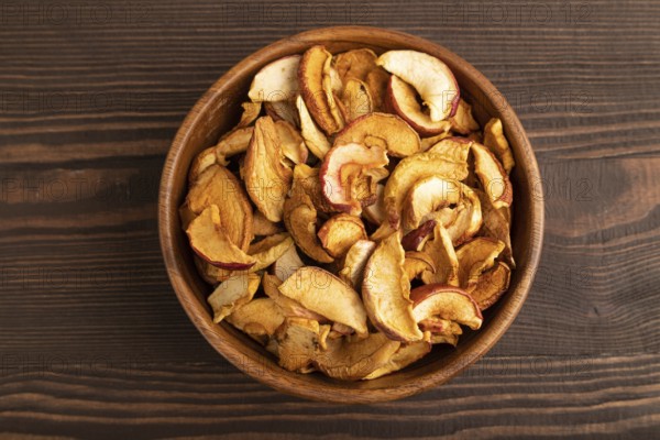 Dried Apples in wooden bowl on brown wooden background. Top view, close up, flat lay. healthy food, minimalism. sweet
