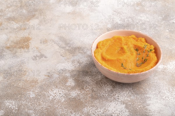 Sweet potato porridge in ceramic bowl on brown concrete background. Diet, healthy eating concept. side view, copy space