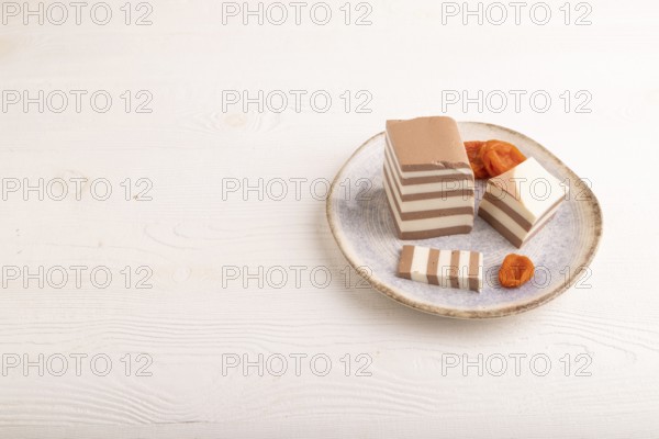 Cocoa and milk jelly with dried apricots on white wooden background, side view, copy space, minimalism