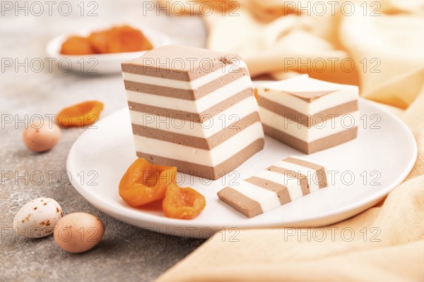 Cocoa and milk jelly with dried apricots on brown concrete background and orange textile, side view, close up, selective focus, minimalism