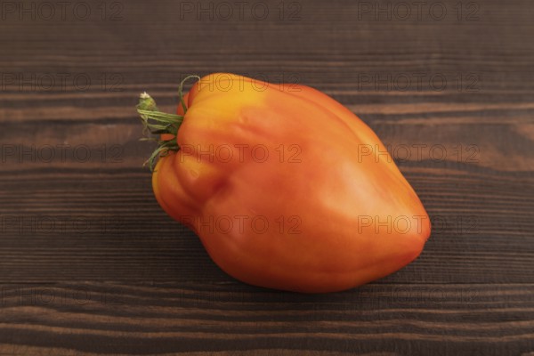 Red Heart Shape tomato on brown wooden background. Side view, close up. healthy food, vegetable, minimalism