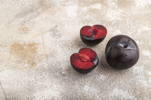 Purple Plum Cut in half on brown concrete background. Side view, copy space. healthy food, vegetable, minimalism