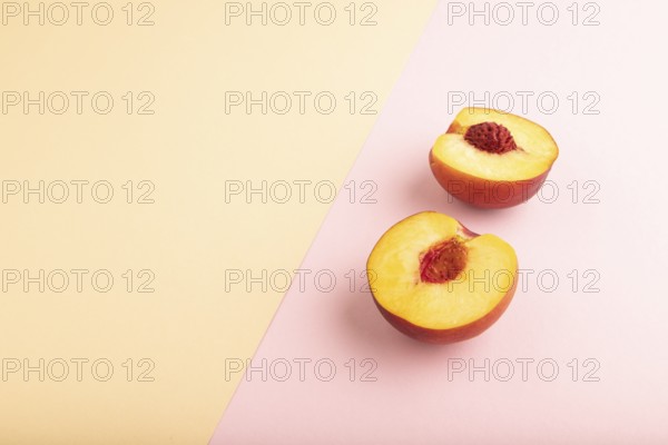 Peach Cut in half on orange and pink paper pastel background. Side view, copy space. healthy food, minimalism