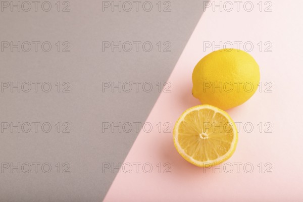 Yellow Lemon Cut in half on gray and pink pastel paper background. Side view, copy space. healthy food, vegetable, minimalism
