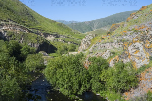 A lush valley crossed by a river, surrounded by tall green mountains under a clear sky, Vorotan River, Syunik Province, Armenia
