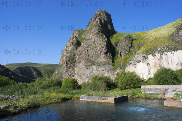 Clear water with spring flows through a lush landscape dominated by huge, rocky mountains, hot spring, Vorotan, Vorotan, Syunik province, Armenia