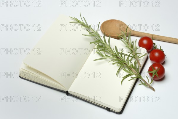 Blank notebook for cooking recipes, cooking spoon with rosemary sprig, tomato