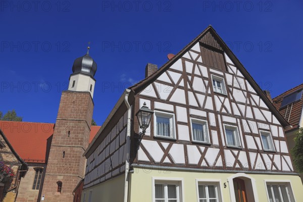 Half-timbered house and tower of the Catholic Church, town of Heideck in the district of Roth, Middle Franconia, Bavaria, Germany