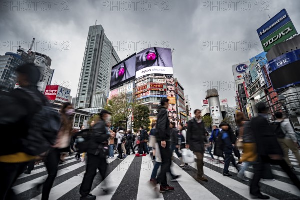 Crowd crossing zebra crossing on a large intersection, motion blur, back modern houses with colorful neon signs, long exposure, Shibuya Crossing, Shibuya, Tokyo, Japan