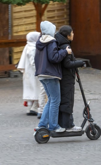 City center, shopping street, Kettwiger Straße pedestrian zone in Essen, 2 young woman on an e-scooter, electric scooter, in front of the opening of the Christmas market, North Rhine-Westphalia, Germany
