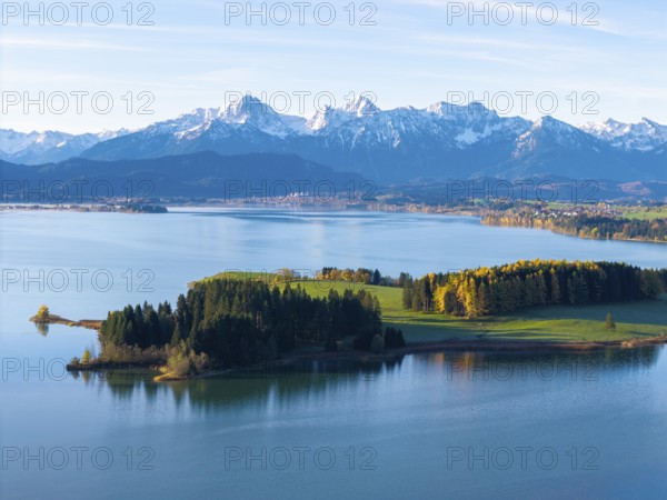 Diverse alpine landscape with a peaceful lake, autumnal wooded hills and snow-capped mountains