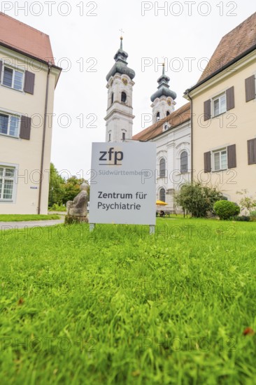 Sign for the Center for Psychiatry with two church towers in the background on a green field, ZFP Zwiefalten, Reutlingen district, Germany