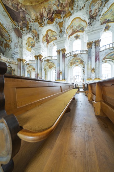 Wooden bench in church interior under artfully decorated baroque frescoes and columns, ZFP Zwiefalten, Reutlingen district, Germany