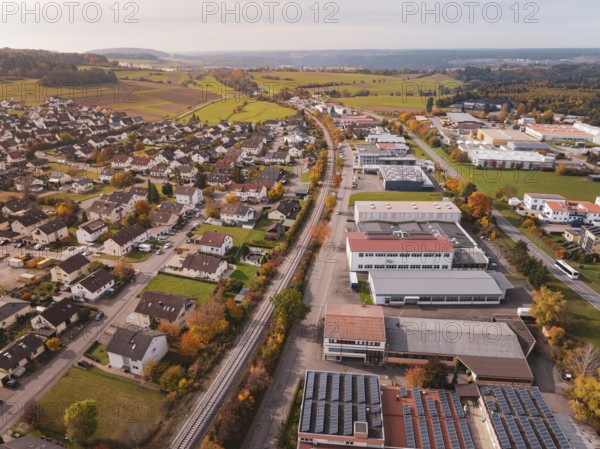 An urban landscape in autumn with a Hermann Hesse Bahn railway line surrounded by houses and industrial buildings, Althengstett, Calw district, Germany