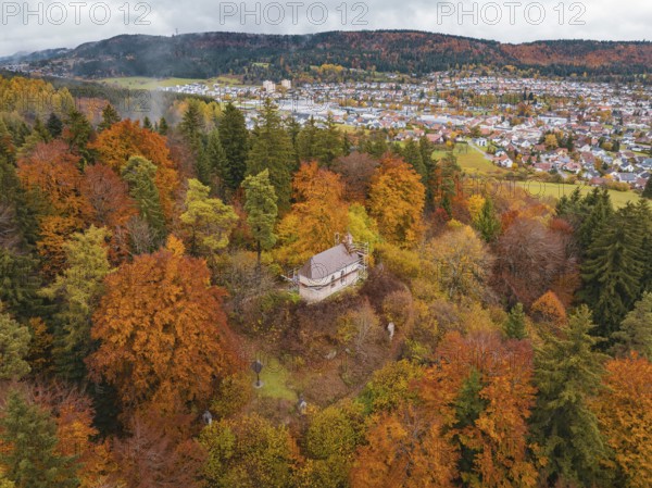 Pavilion in the middle of a colorful autumn forest with a view of a city in the distance under a cloudy sky, Wehingen, Tuttlingen district, Germany