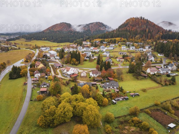 Aerial view of a village surrounded by autumnal hills and clouds of fog, Wehingen, Tuttlingen district, Germany