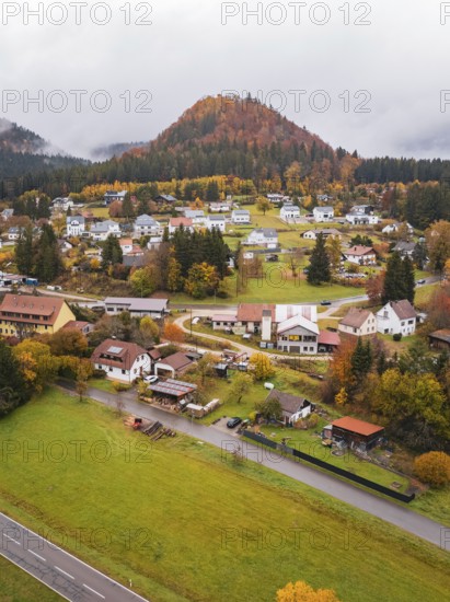 Small village in autumn surroundings with colorful trees and foggy hills in the background, Wehingen, Tuttlingen district, Germany