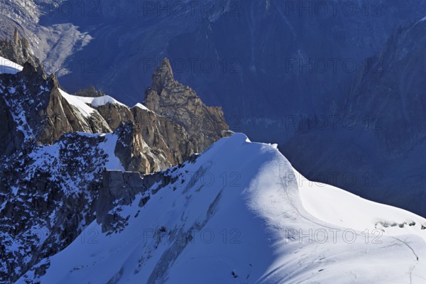 Rugged rocks jut out of a snow-covered mountain, viewing platform, Aiguille du Midi mountain station, Chamonix-Mont-Blanc, Haute-Savoie, France