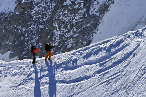 Two mountaineers run across a snow-covered mountain ridge, Aiguille du Midi, Chamonix-Mont-Blanc, Haute-Savoie, France