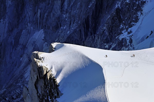 A group of mountaineers runs across a snow-covered mountain, Aiguille du Midi, Chamonix-Mont-Blanc, Haute-Savoie, France