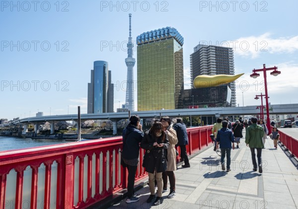 Visitors on the Azuma Bridge, Sumida City Skyline, Sumida City Office, Tokyo Skytree, Asahi Beer Hall and Asahi Headquarters with Asahi Flame, Asakusa, Tokyo, Japan